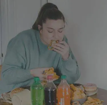 En kvinna omgiven av läsk och munkar hetsäter kringlor.