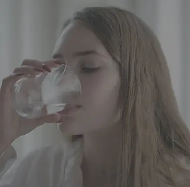 Ung kvinna som dricker ett glas vatten.
